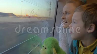 小男孩和妈妈坐在火车车厢里的靠窗的地方看着外面